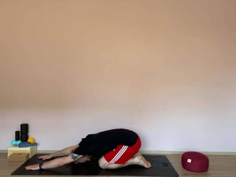 Person in der Kindeshaltung (Balasana) auf einer Yogamatte – eine beruhigende Übung im Yoga für Anfänger, ideal zum Entspannen und Loslassen.