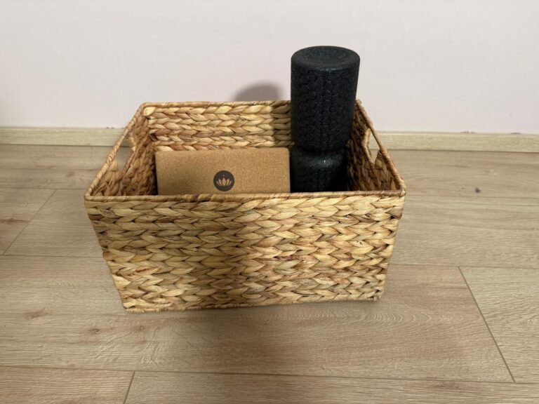 Geflochtener Aufbewahrungskorb mit Yogablock und Faszienrolle auf hellem Holzboden – praktische Ordnungslösung für Yoga-Zubehör zuhause.