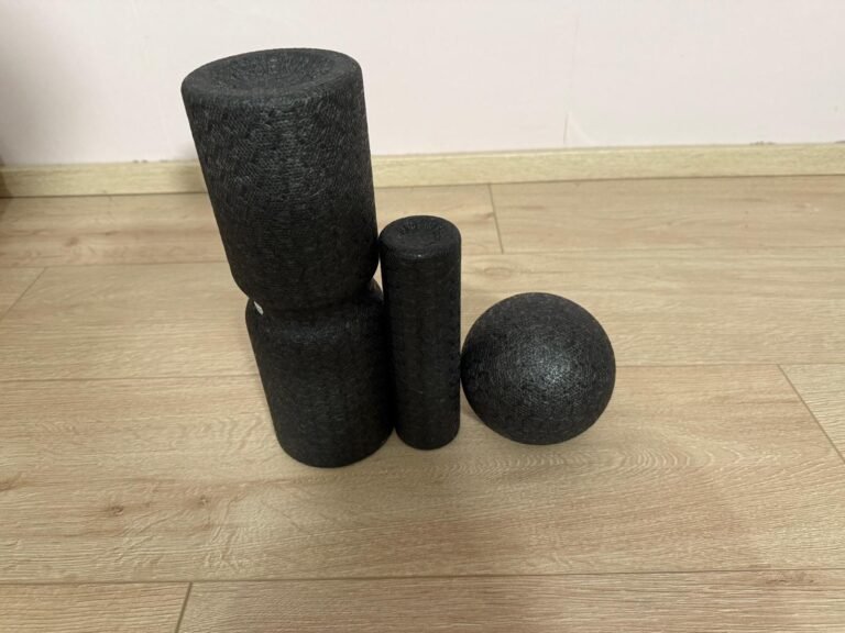 Faszien-Set bestehend aus zwei Rollen, einem Faszienball und einer Doppelrolle auf hellem Holzboden – ideales Equipment zur Muskelentspannung, Regeneration und Vorbereitung auf Yogaübungen zuhause.