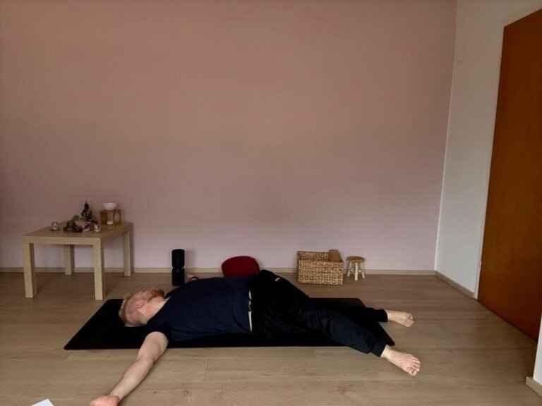 Mann macht Yoga Anfänger Übung: sanfte Rücken-Drehung auf der Matte zur Entspannung und Mobilisierung der Wirbelsäule.