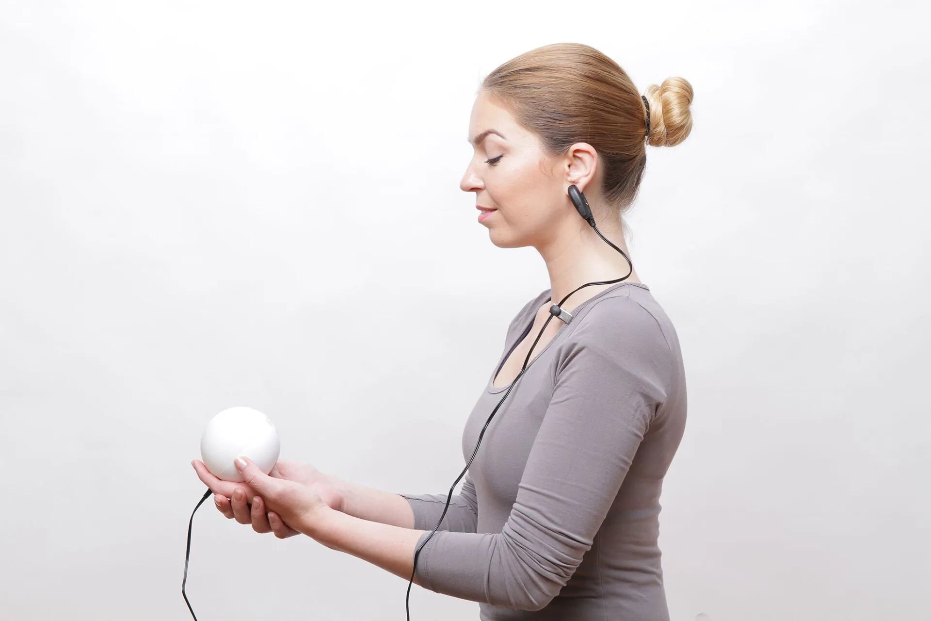 Frau misst mit dem Qiu Ball und Ohrclip ihr Stresslevel – HRV-Biofeedback zur Stress Messung und Entspannung.