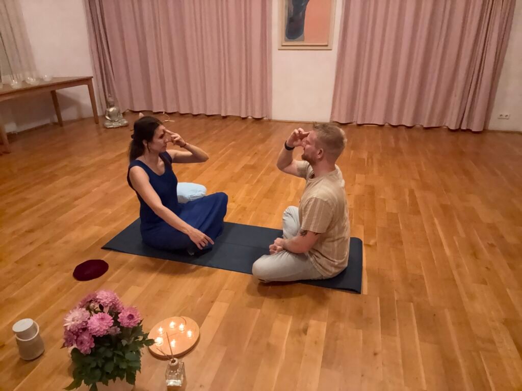 Frau und Man praktizieren gemeinsam Atemübungen zur Entspannung im Schneidersitz auf einer Yogamatte