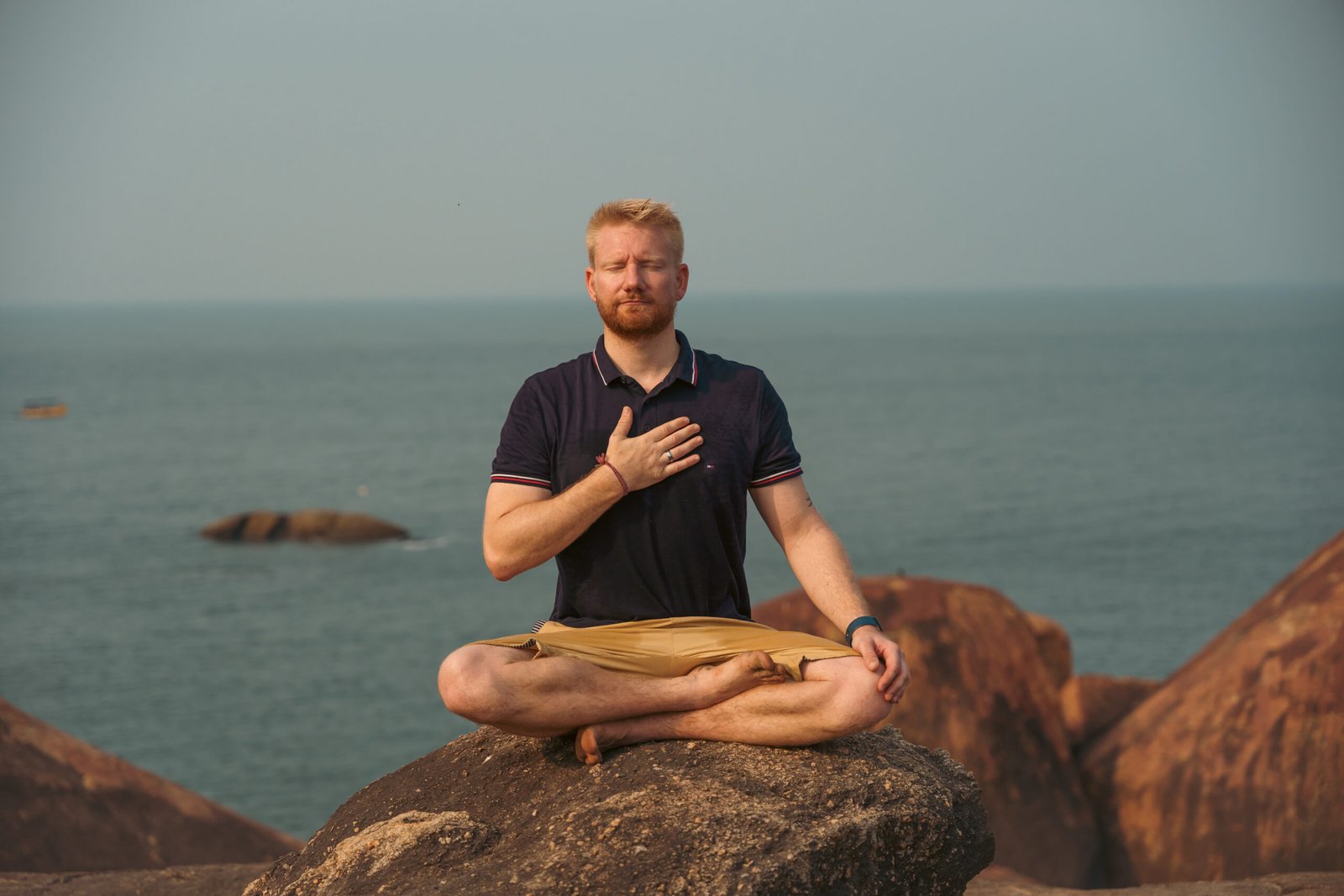 Mann meditiert am Meer und praktiziert kohärente Atmung zur Förderung von Herzkohärenz und innerer Ruhe während einer Herzkohärenz Meditation.