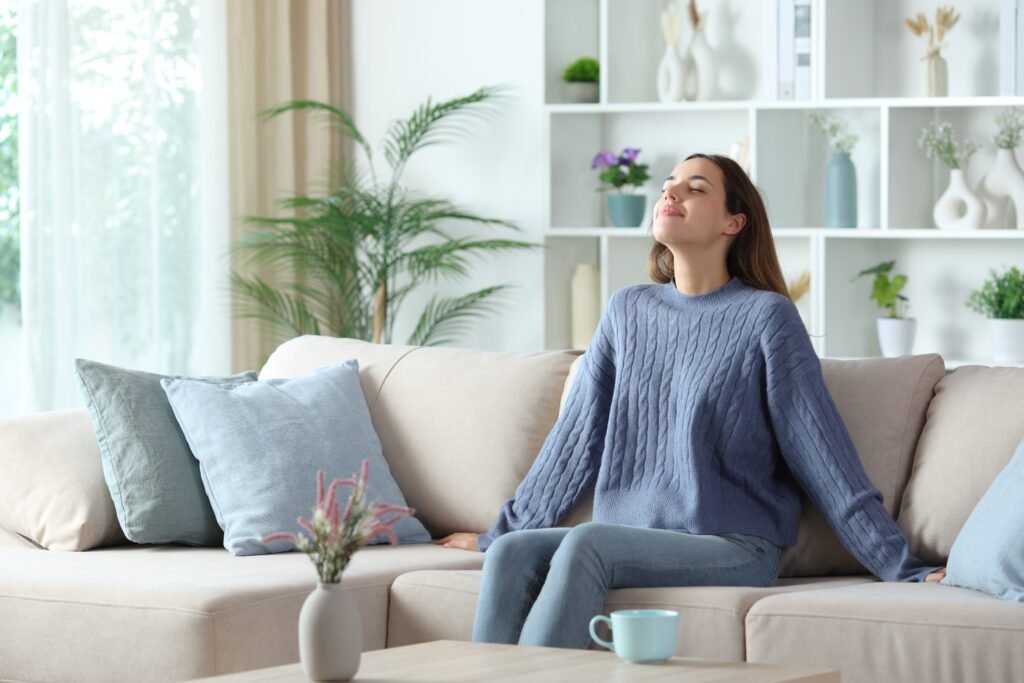 Frau praktiziert Herzkohärenz Atmung und kohärente Atmung zur Entspannung auf dem Sofa