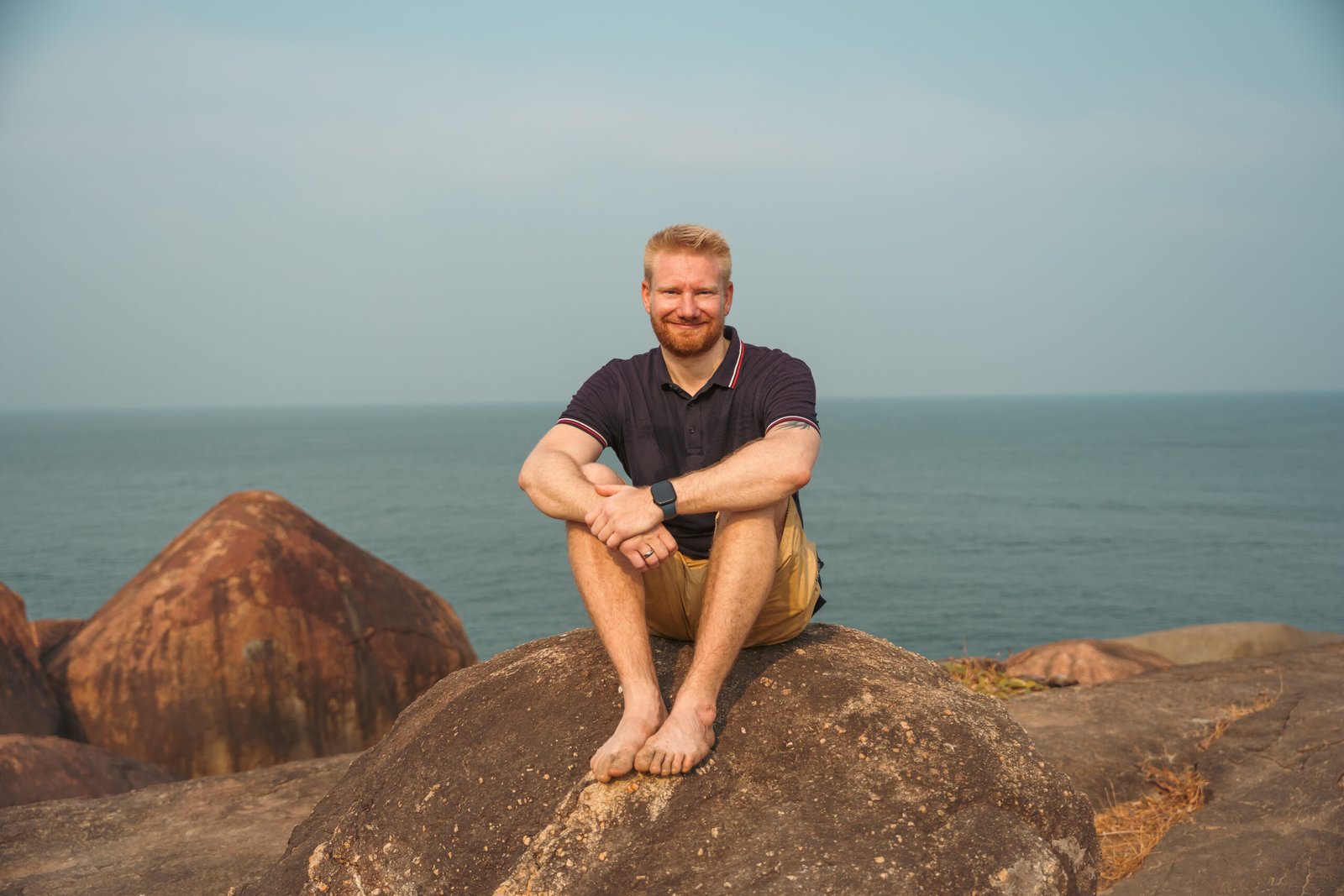 Mann sitzt auf Felsen am Meer in Goa, Indien während eines Yoga Retreats in Goa
