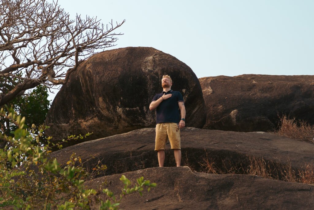 Mann steht meditierend auf einem Felsen in der Natur und praktiziert Herzkohärenz Atmung und Herzkohärenz Meditation zur Regulation des Nervensystems.