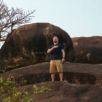 Mann steht meditierend auf einem Felsen in der Natur und praktiziert Herzkohärenz Atmung und Herzkohärenz Meditation zur Regulation des Nervensystems.