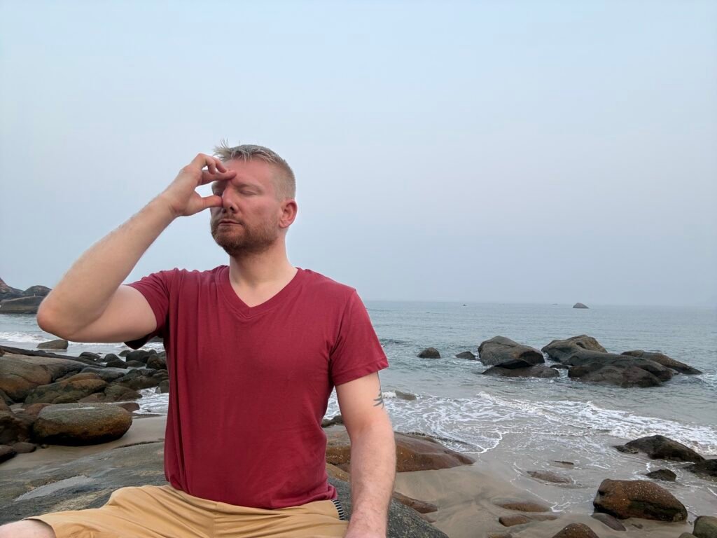 Meditation und Breathwork am Strand – Mann praktiziert Atemübung zur Stressreduktion und Nervensystem-Regulation am Meer
