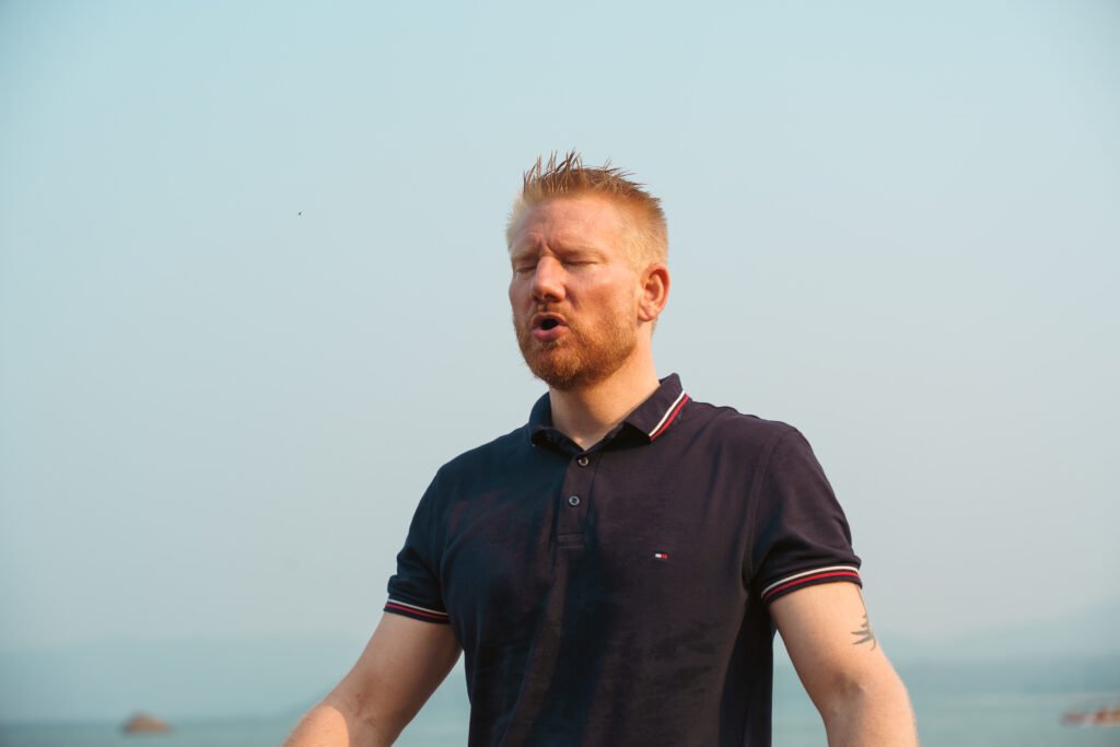 Mann praktiziert eine breathwork session am Meer zur Regulierung des Nervensystems und zur Förderung von innerer Balance